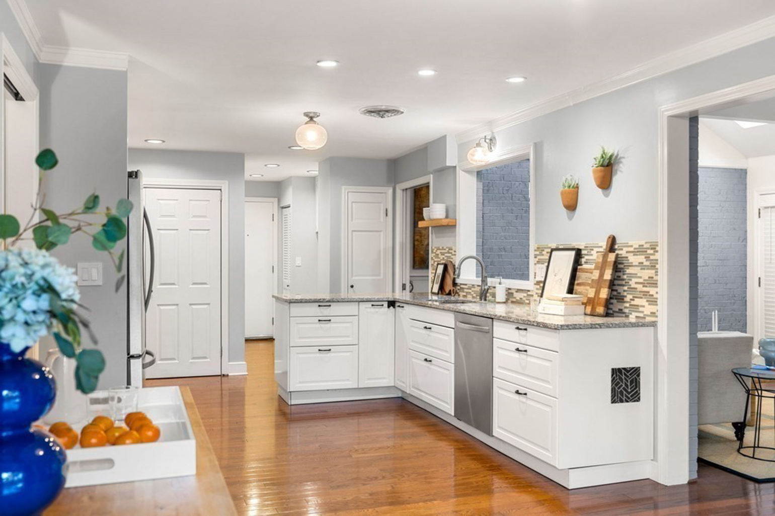 Semi-flush mount ceiling lights, white cabinets, wooden floor kitchen.