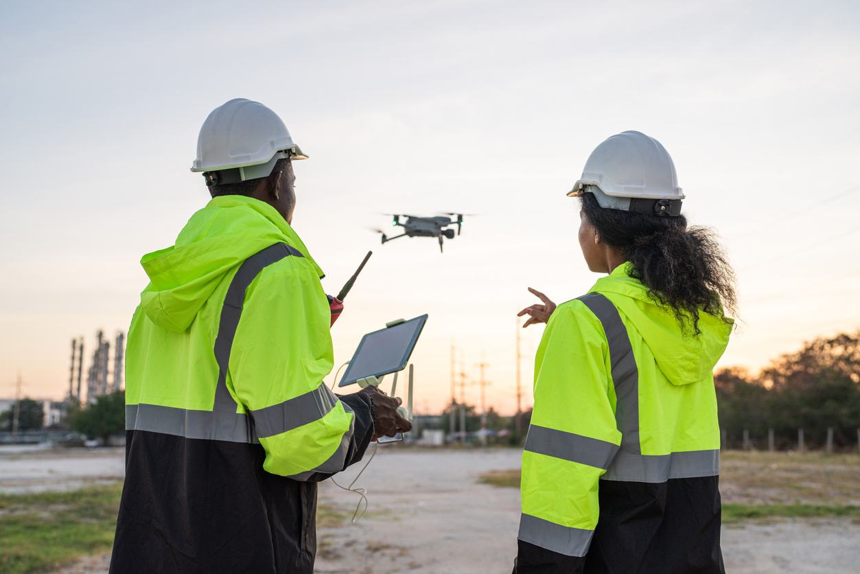 Two construction professionals navigating a drone on the construction site.