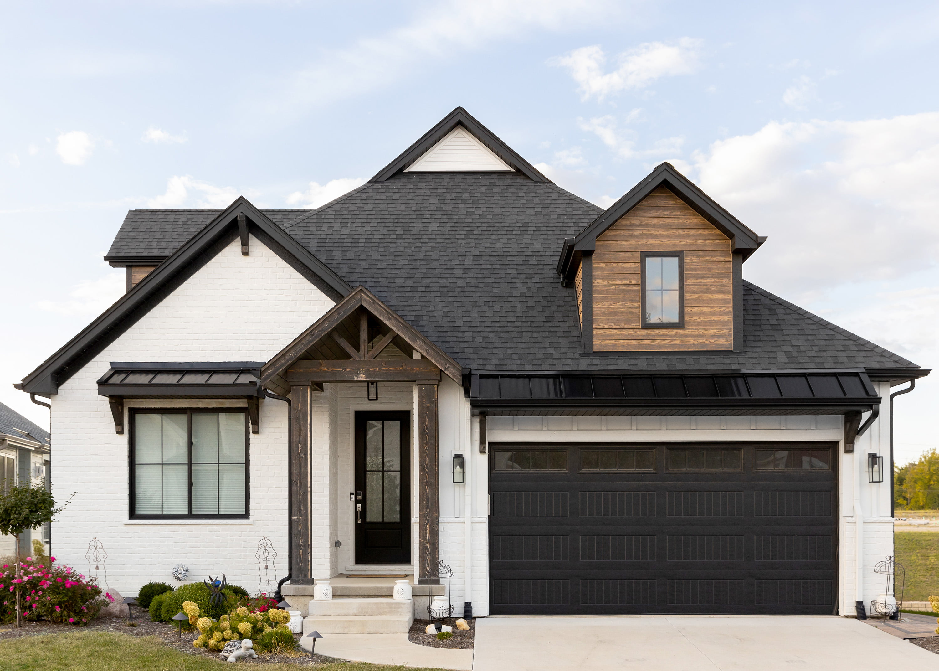 A house with white siding, a black front door, and wooden features.