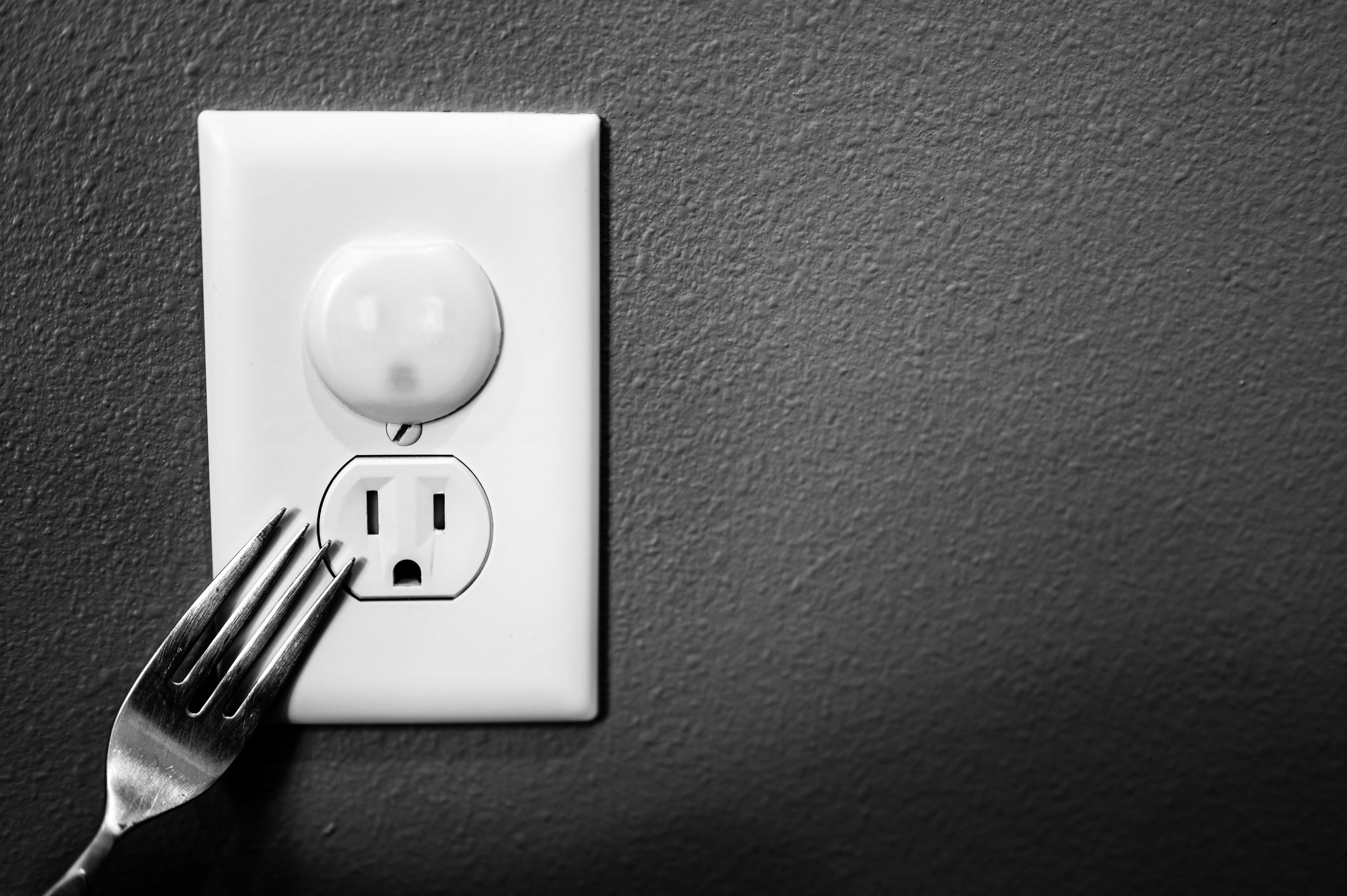 A fork touching the outlet with the safety cover.