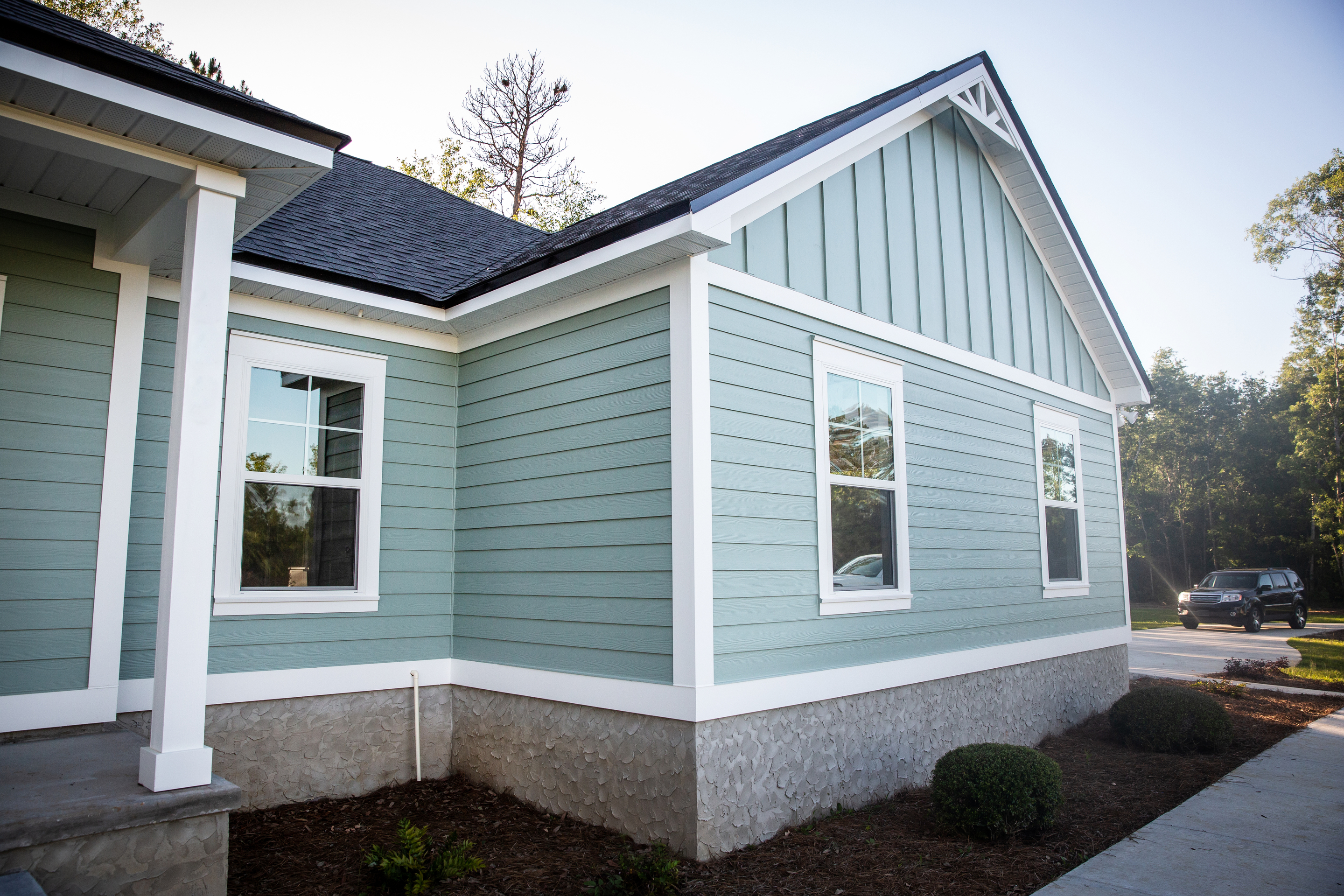 Exterior of a home with teal siding and vinyl window trims